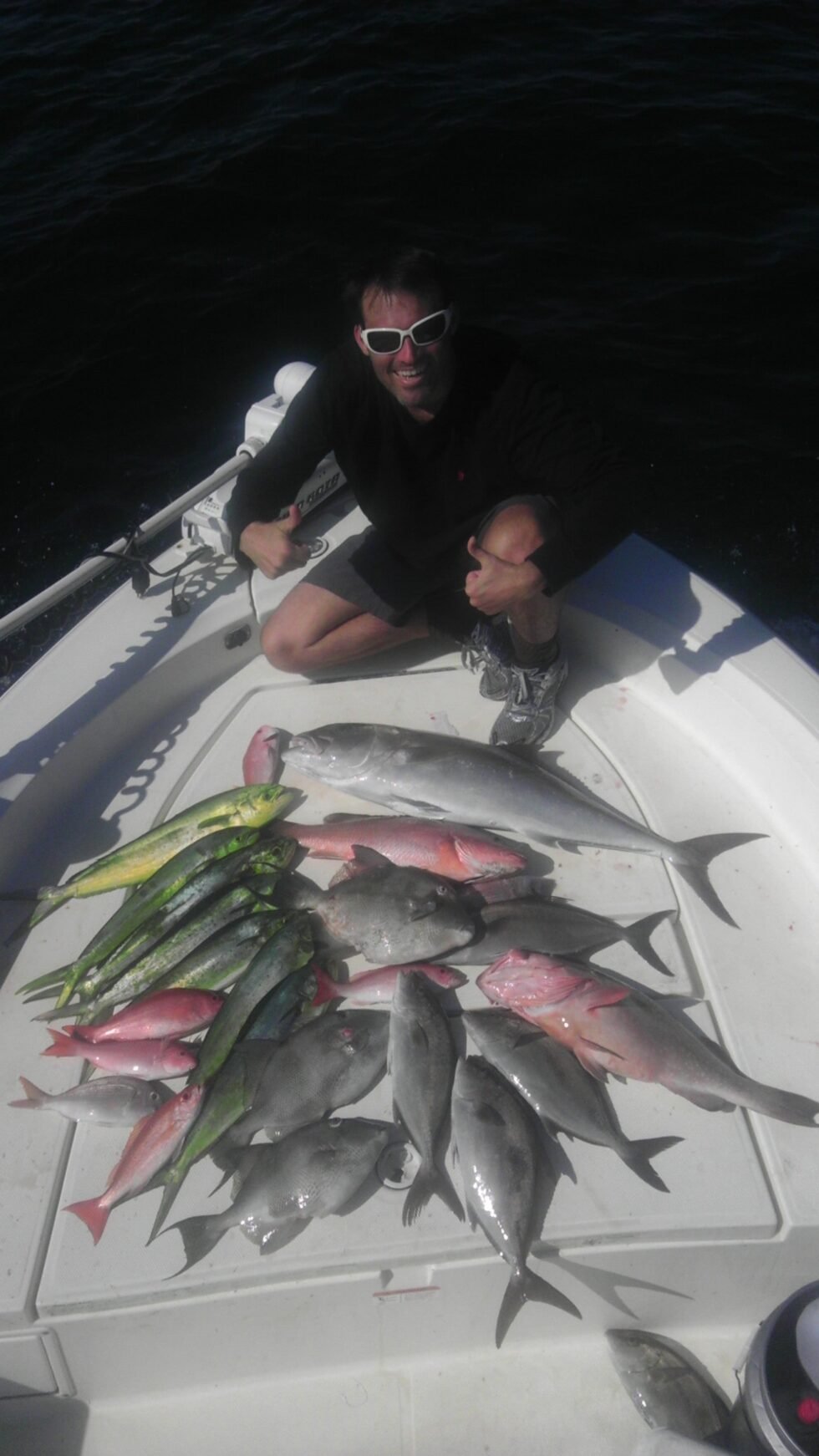 A man sitting on a boat with a bunch of fish.