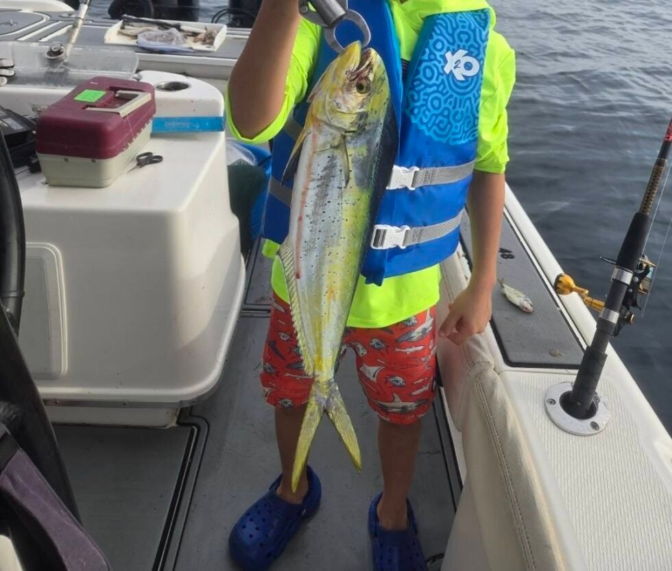 Young angler holding a mahi mahi during a fishing charter